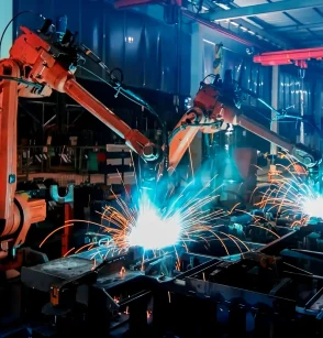 Large factory robotic arms are spraying sparks to weld car frame